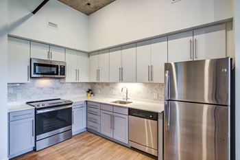 An empty kitchen with stainless steel appliances and white cabinets